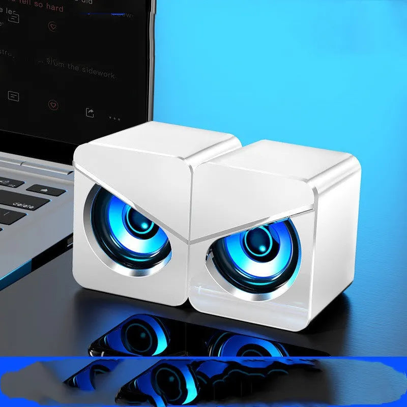 Small black and white plastic desktop computer speakers with 3.5mm cable and battery compartment