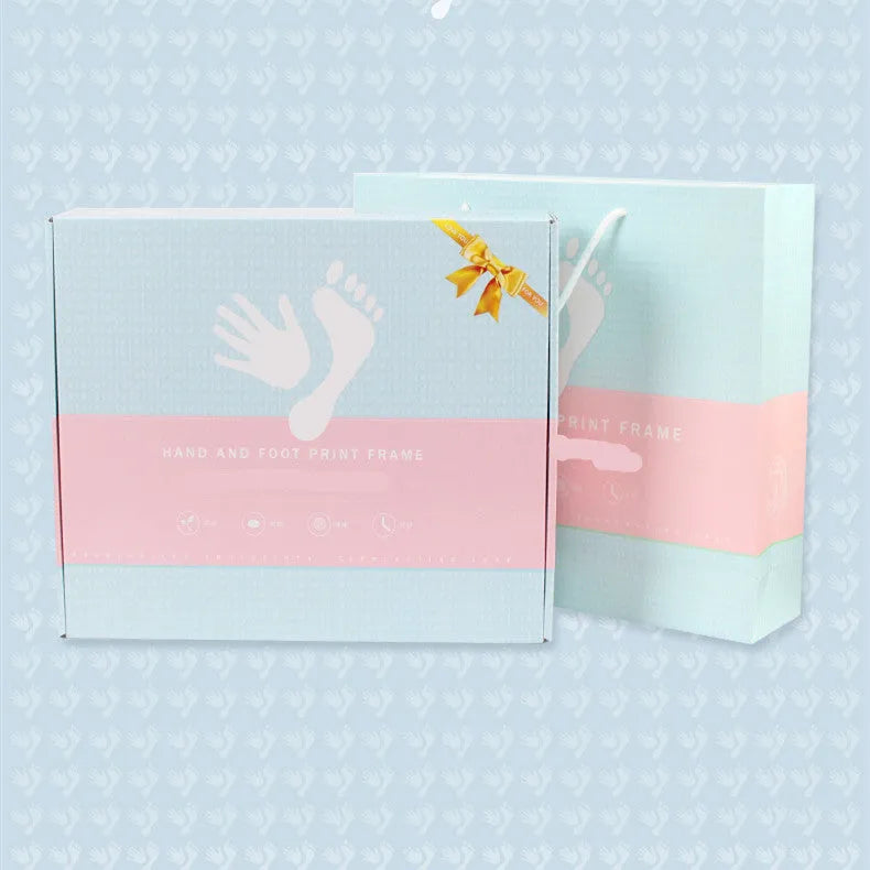 Modern DIY baby hand and foot photo frame in white on a shelf, showing handprint and footprint display area.