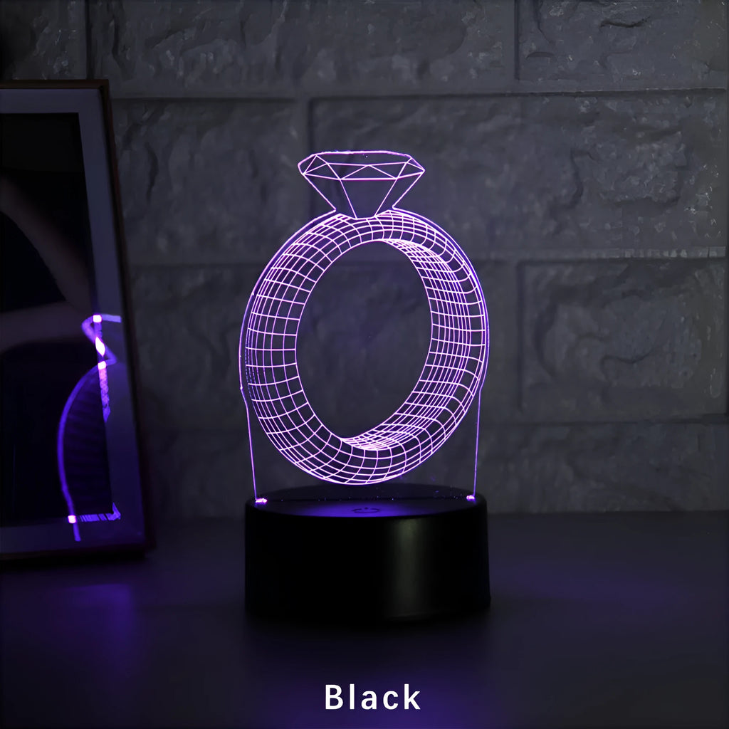 3D LED night light projecting a glowing diamond ring design on a black base with colour-changing effects.