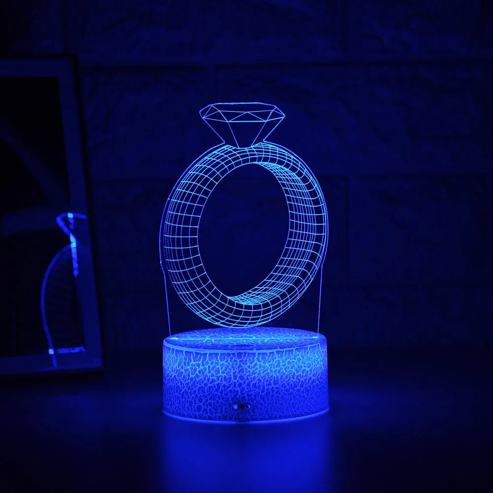 3D LED night light projecting a glowing diamond ring design on a black base with colour-changing effects.