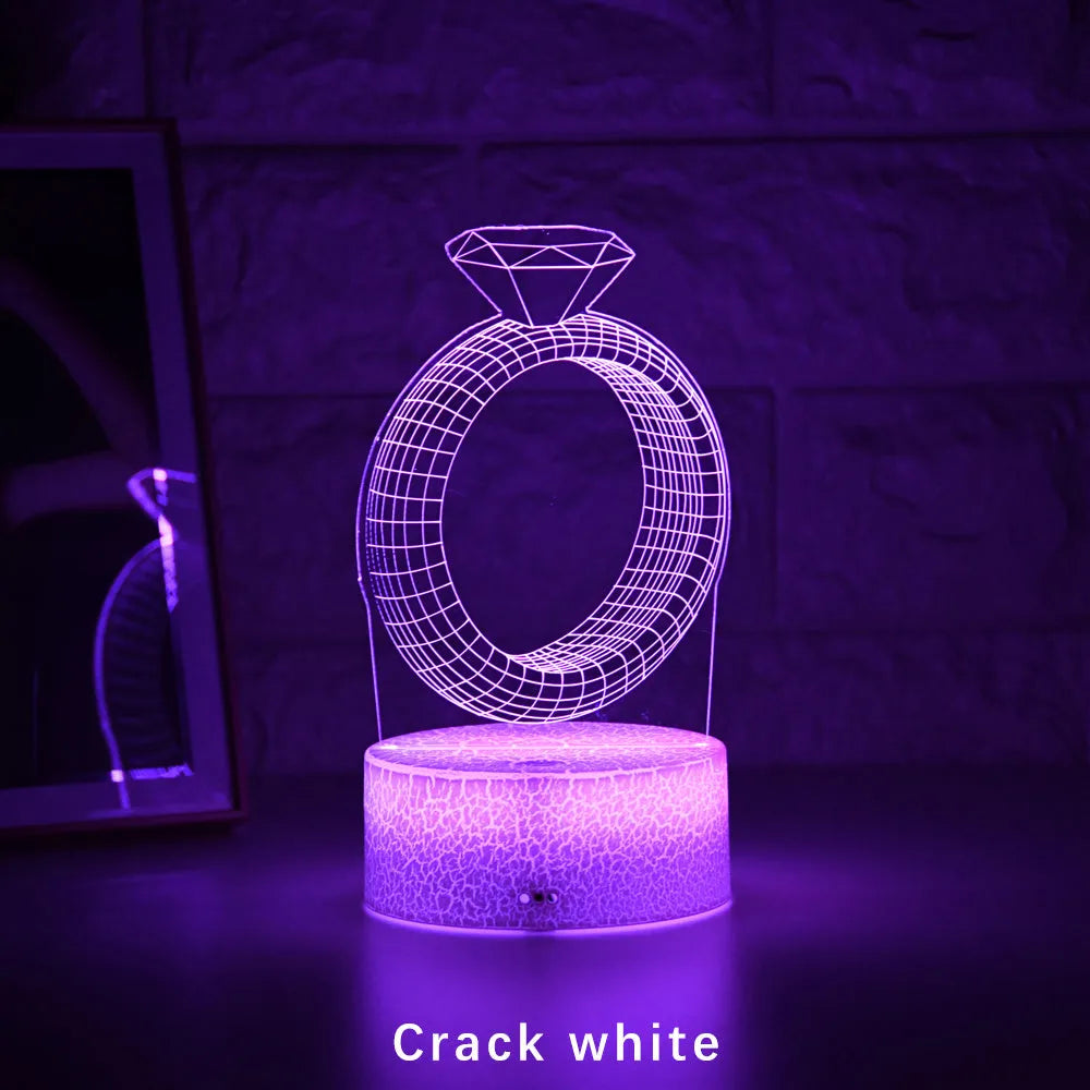 3D LED night light projecting a glowing diamond ring design on a black base with colour-changing effects.