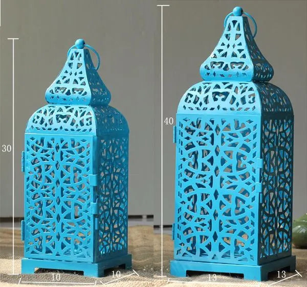 A tall blue geometric metal candle holder with hollow design, holding a tea light on a wooden table.