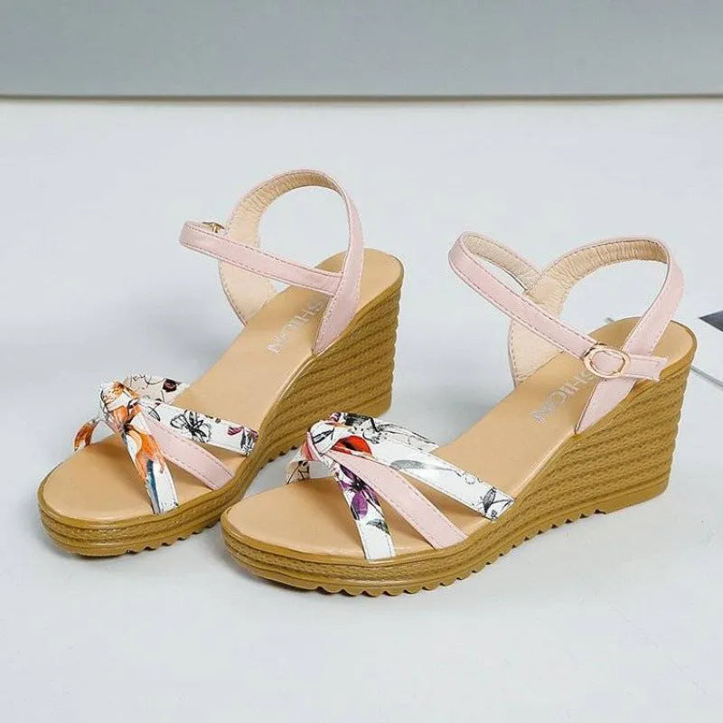 Pink women's wedge sandals with peep-toe, thick heel, and a single buckle fastening on a white background.