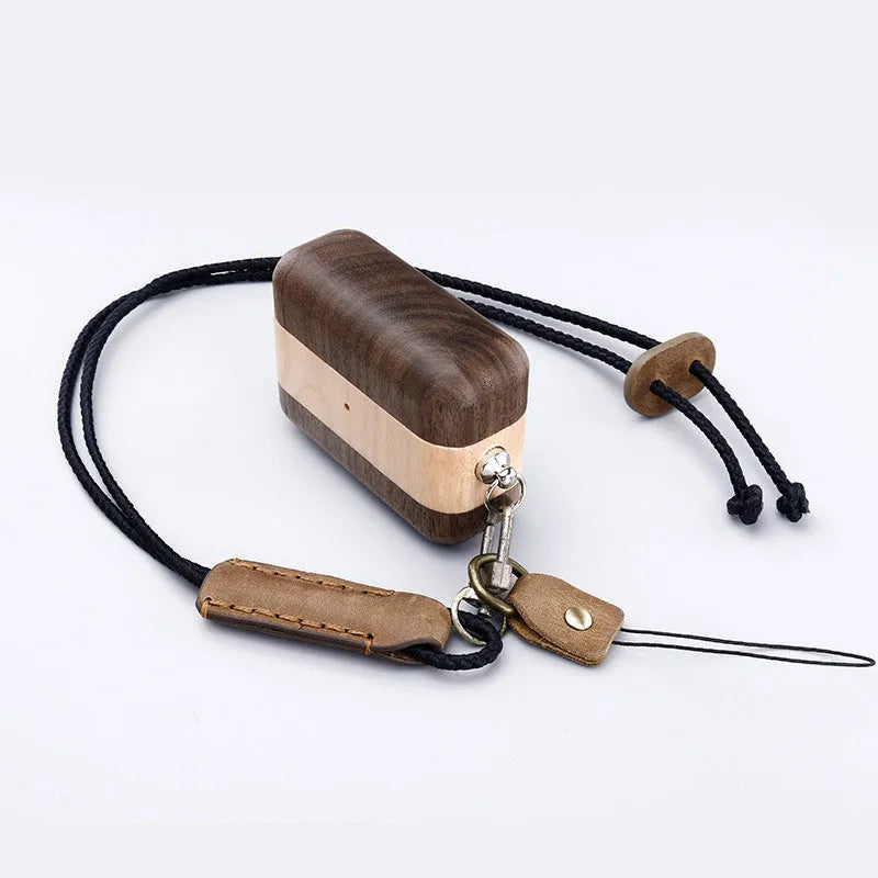 Solid wood earphone sleeve in walnut next to compatible wireless earphones on a wooden table.
