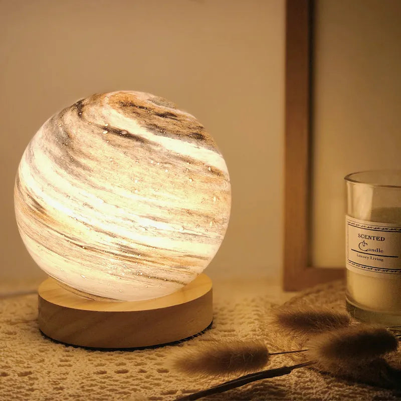 Nordic-style amber glass table lamp with USB cable on a wooden bedside table.