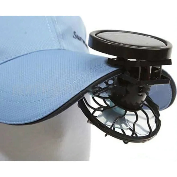 Black portable solar fan panel with clip, shown in an outdoor setting.