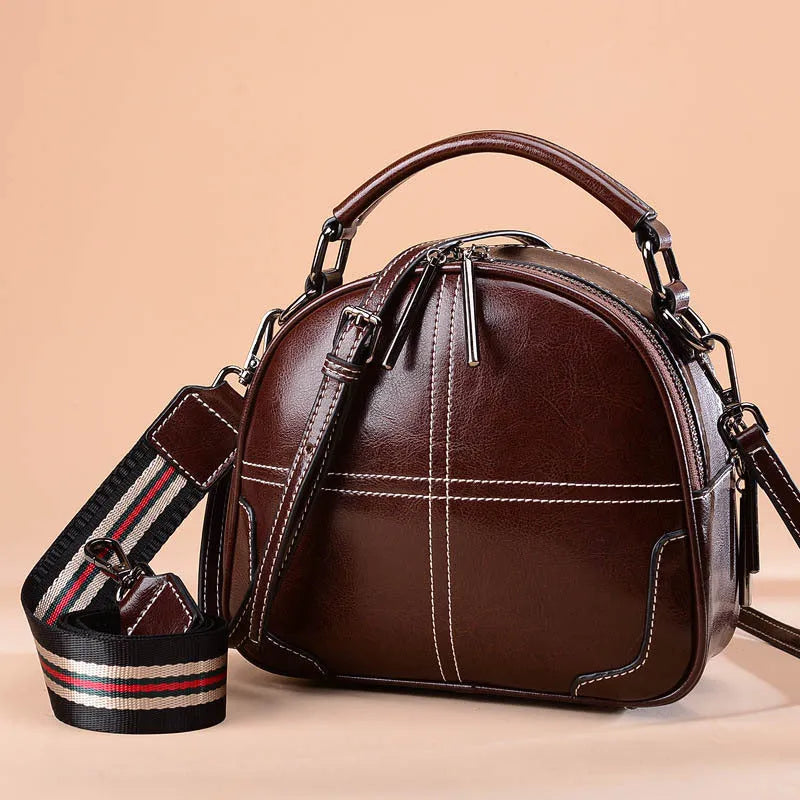 Simple round leather handbag with a soft handle and zipper, shown in wine red colour.