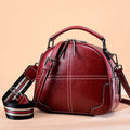 Round leather women's handbag with soft double handles and a zipper opening.