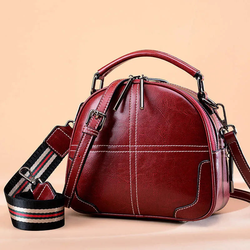 Round leather women's handbag with soft double handles and a zipper opening.