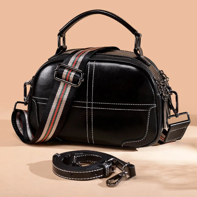 Round leather shoulder bag in wine red with soft handles and a zipper closure.