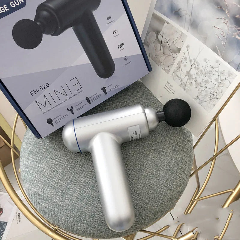 Grey handheld fascia gun massager on a plain background, showing ergonomic handle.