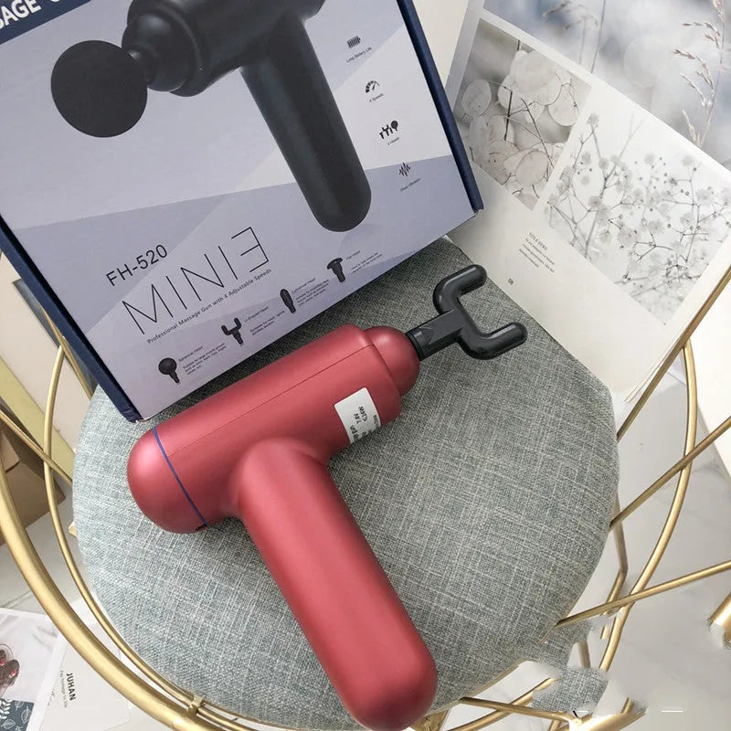 Grey handheld fascia gun massager on a plain background, showing ergonomic handle.