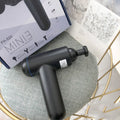 Grey handheld fascia gun massager on a plain background, showing ergonomic handle.