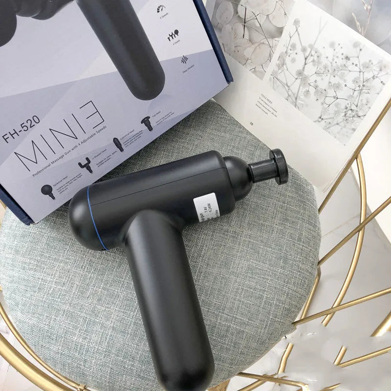 Grey handheld fascia gun massager on a plain background, showing ergonomic handle.