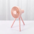A small black adjustable desktop fan with flexible octopus tripod legs and a bending head on a wooden desk.