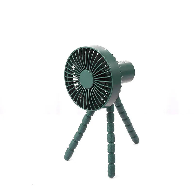 A small black adjustable desktop fan with flexible octopus tripod legs and a bending head on a wooden desk.