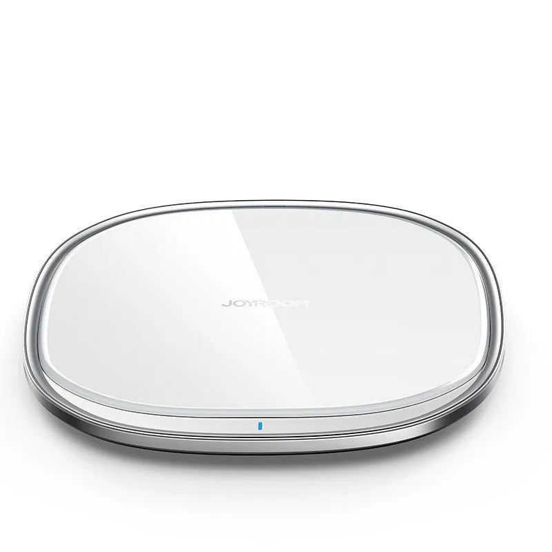 Black 15W wireless charging pad with glass top on a wooden desk next to a mobile phone.