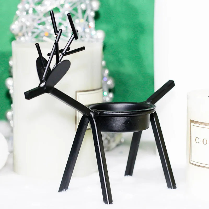 Black iron Christmas candlestick with deer and elk bracket design on a table.