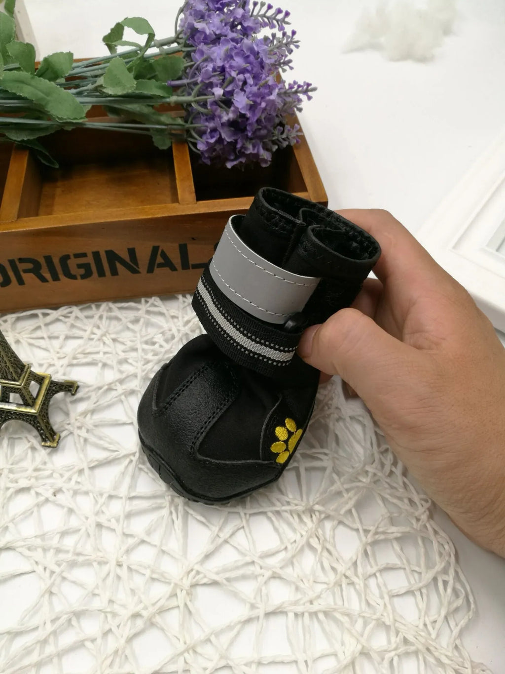 Black pet dog shoes with waterproof PVC sole and adjustable fuzzy belt on a light background