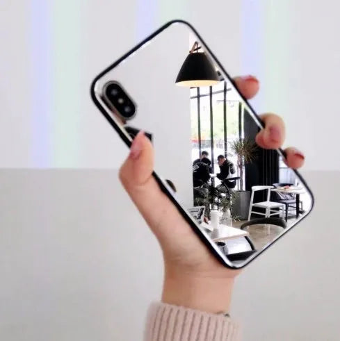 Black mirror back cover phone case for Apple iPhone X, 11, 12, 7, 8, and 6 models on a table.