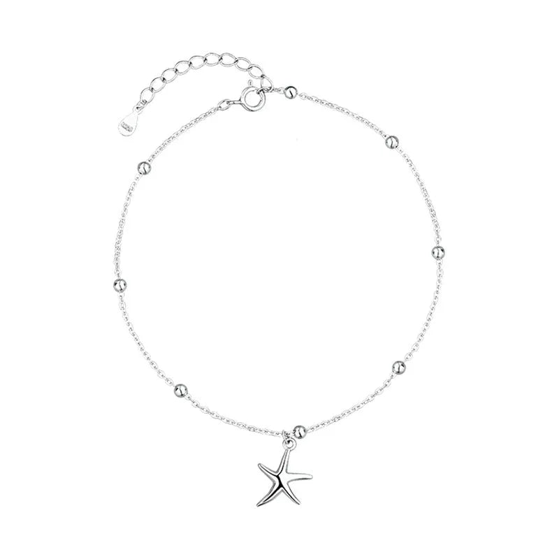 Close-up of a sterling silver anklet with a small starfish charm on a chain of tiny round beads.