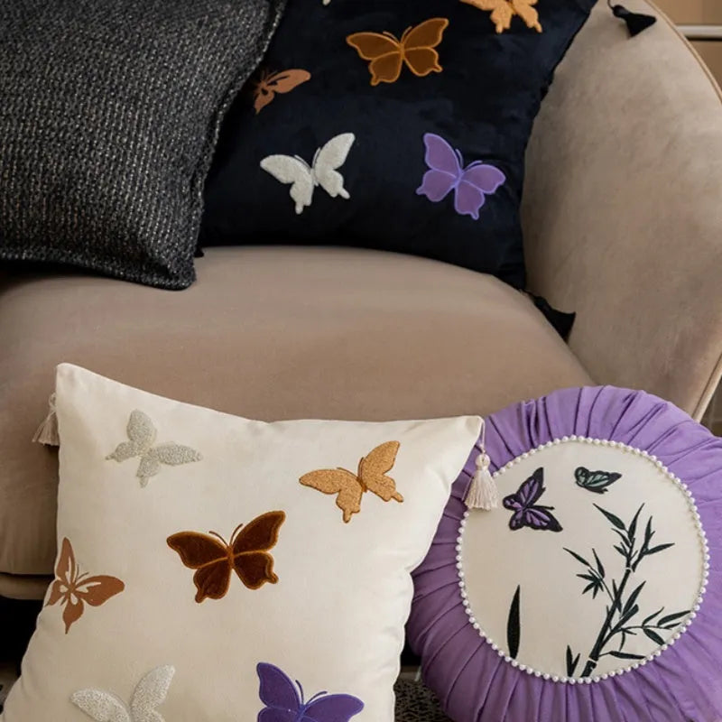 Square decorative cushion with Chinese-style butterfly embroidery in beige, black, and purple colours.