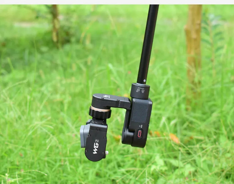 Black retractable aluminium selfie stick extended in hand next to a smartphone.