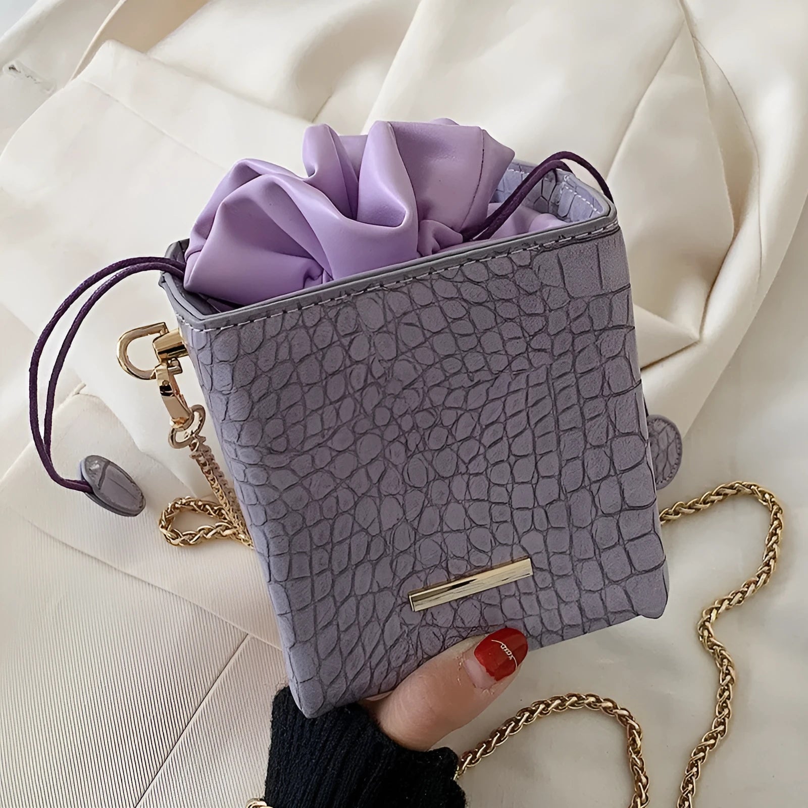 Green women's bucket-style messenger bag with a detachable silver chain strap, shown with drawstring top open.