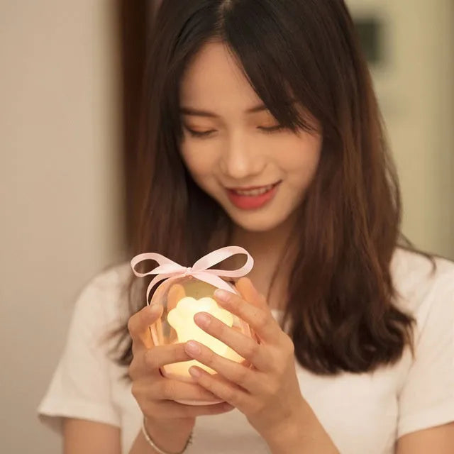 Pink cat paw shaped USB rechargeable night light with soft glow on a desk.