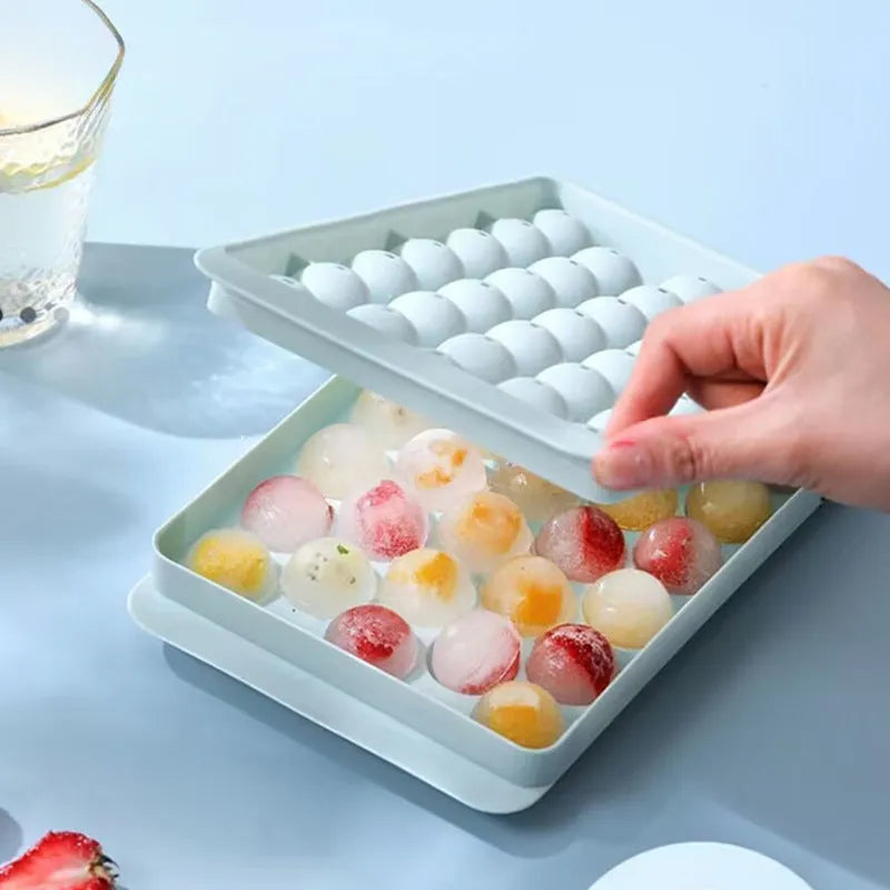 Blue silicone ice tray with lid producing 33 large round ice spheres on a kitchen counter