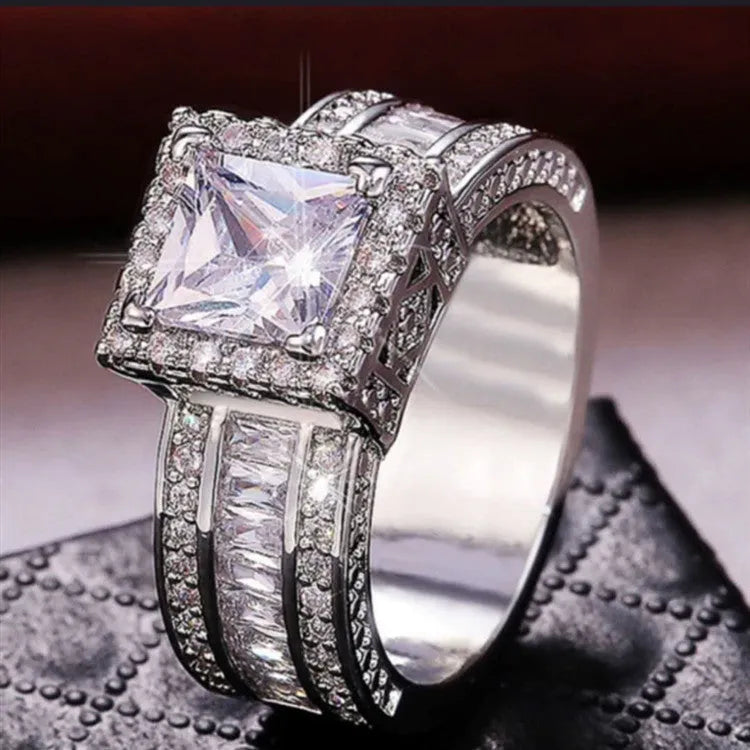 A geometric silver-tone women's ring with a round design element on a model's hand.