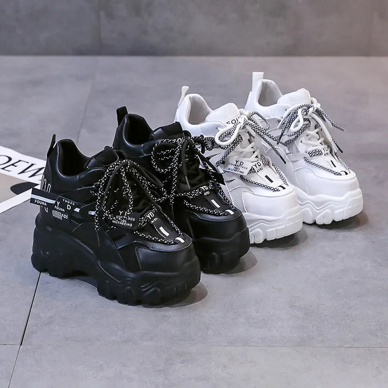 White and black women's low-top platform trainers with mesh upper and cross-strap.