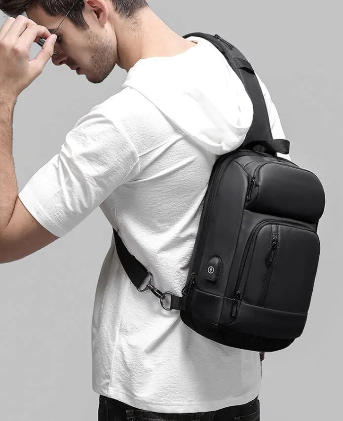 Black medium outdoor PVC shoulder bag with an air cushion strap and organiser pockets.