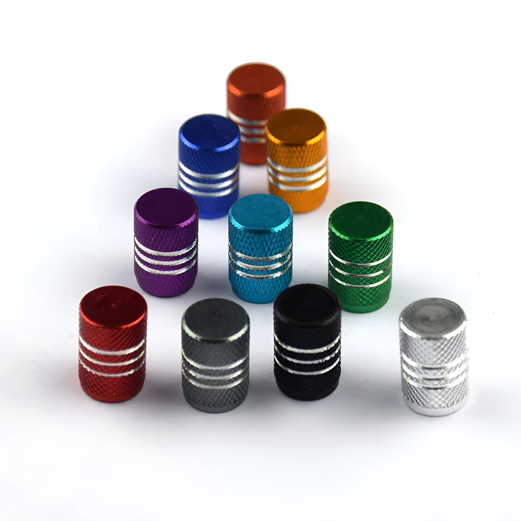 Set of coloured aluminium alloy tyre valve caps for car wheels on a grey background.
