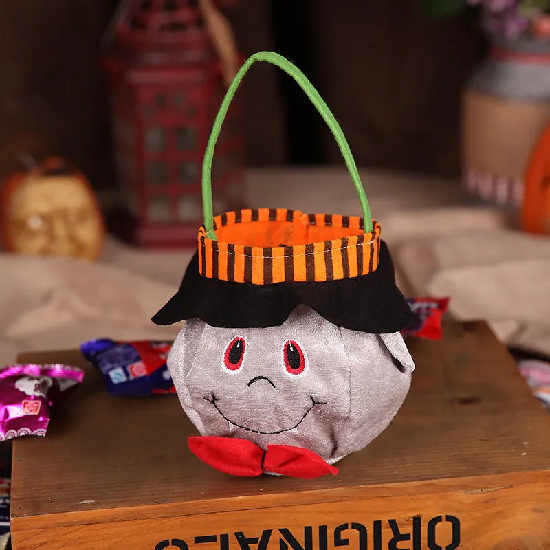 Square black Halloween candy bag with a pumpkin pattern, held by a handle.