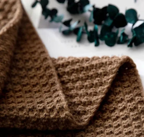 Nordic-style knit blanket with fringe trim in a neutral colour on a sofa