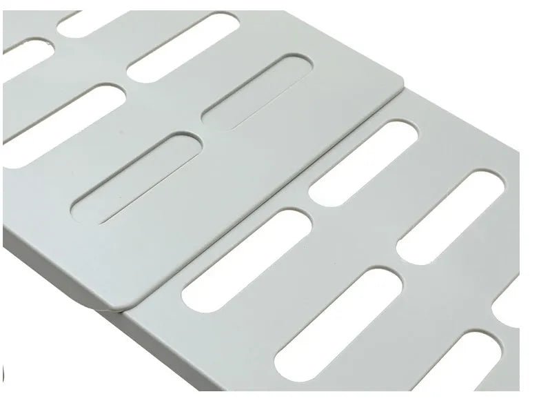 White telescopic plastic storage rack extended to full height with kitchen utensils organised on shelf