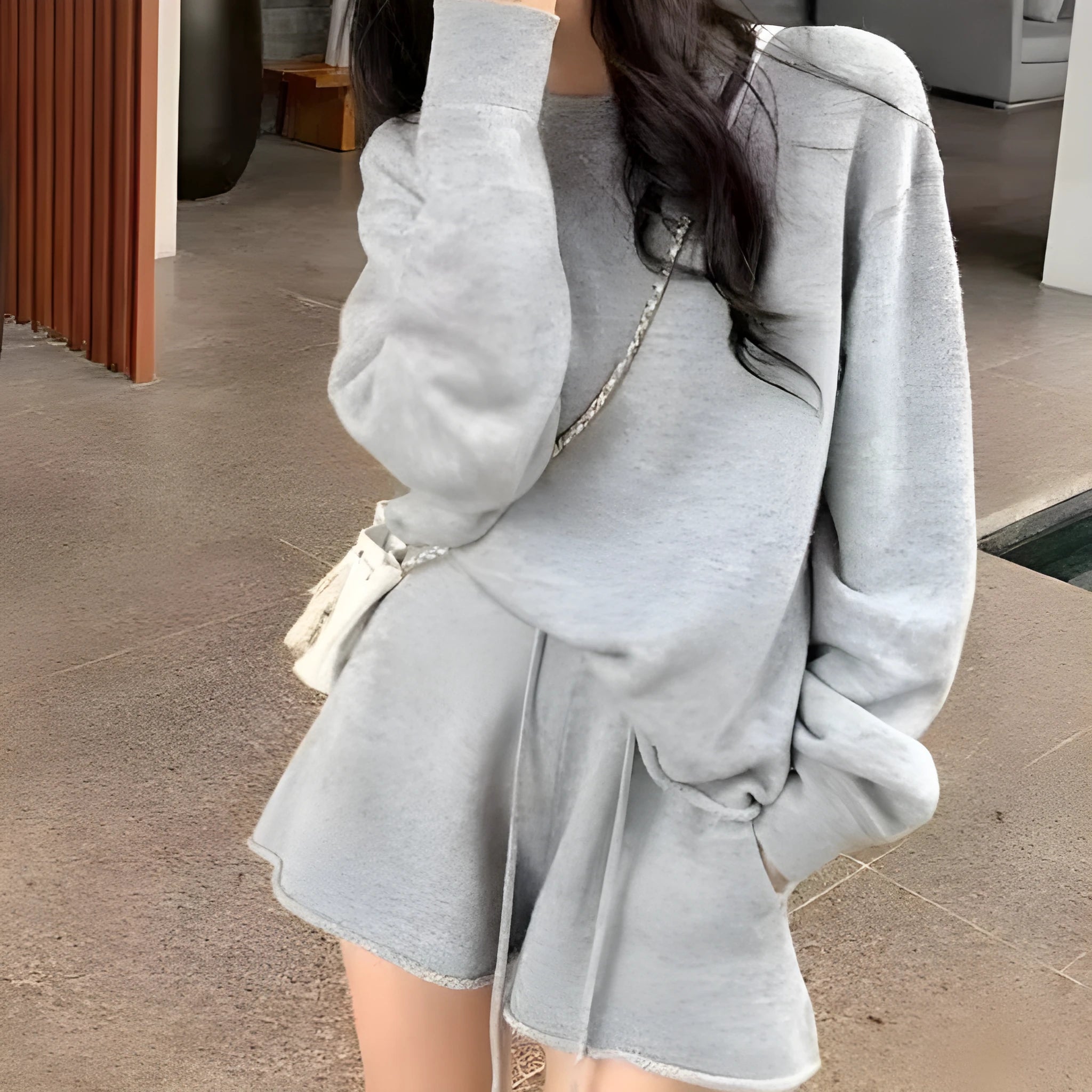 Woman wearing a loose beige knitted long-sleeve sweater and wide-leg shorts set, casual two-piece outfit.