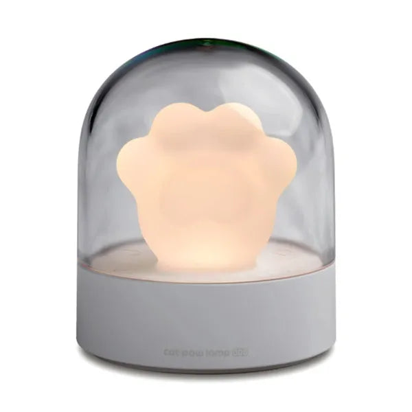 Pink cat paw shaped USB rechargeable night light with soft glow on a desk.