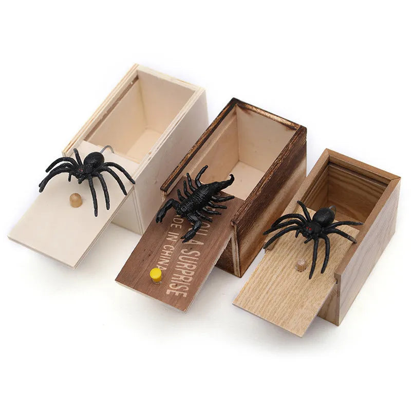 Wooden prank scare box closed, with a lifelike jumping spider toy next to it.