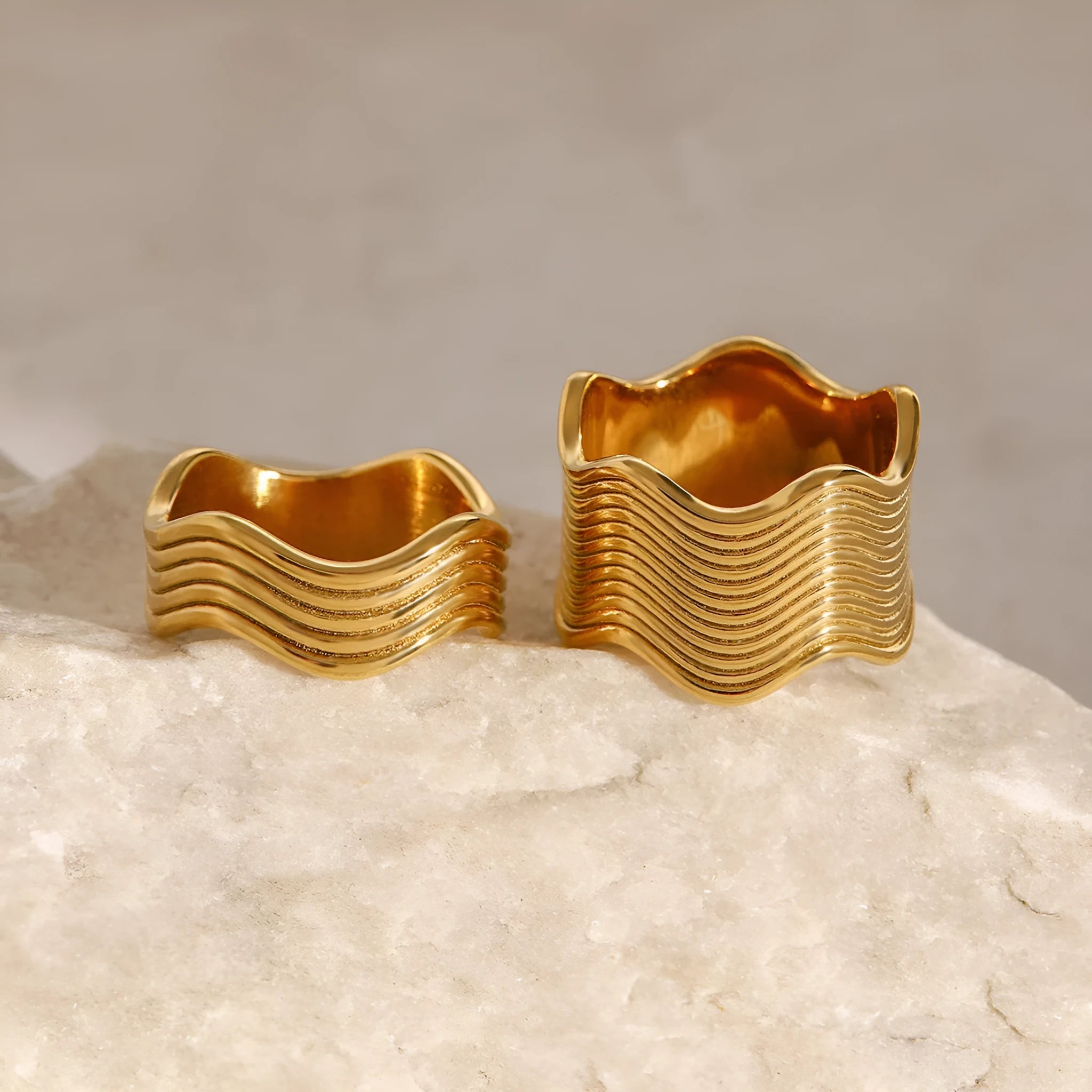 Stainless steel geometric wave ring with a wide band and electroplated finish.