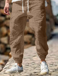 Men's straight leg linen trousers in army green with an elasticated waistband laid flat.