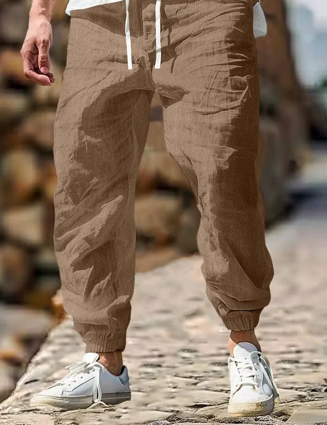 Men's straight leg linen trousers in army green with an elasticated waistband laid flat.