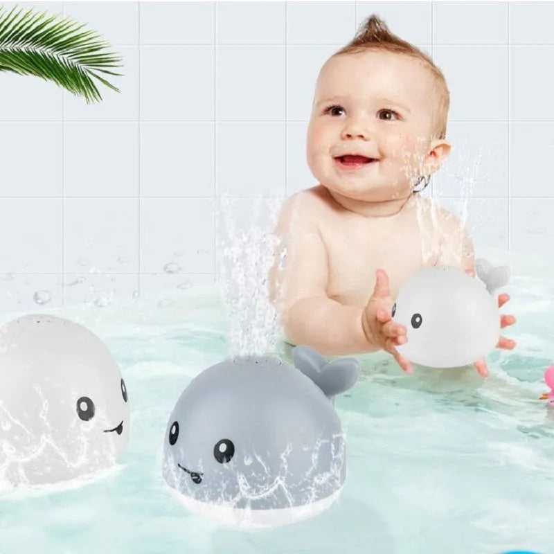 Whale-shaped baby bath toy with automatic water spray, flashing lights, and music on a base.