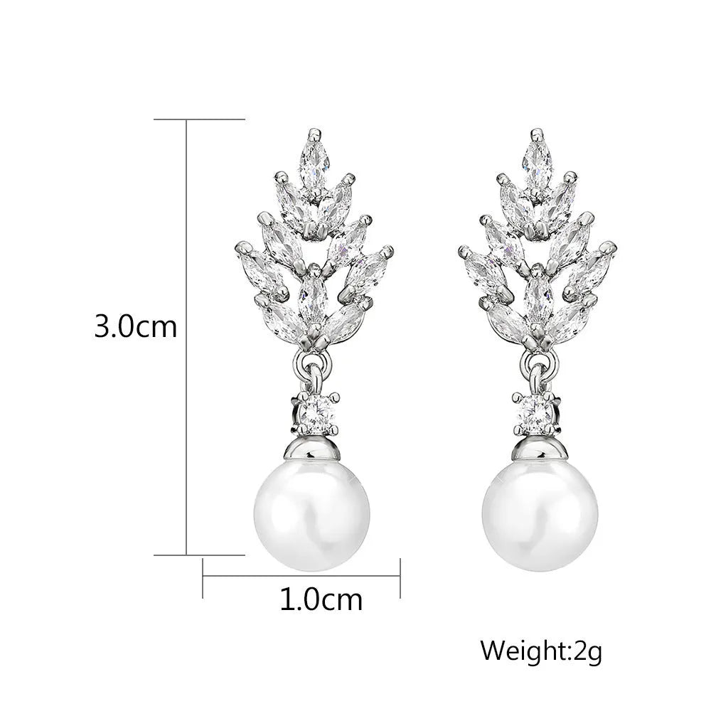 Geometric flower-shaped earrings with micro inlaid zircon and pearl details on a gold-toned metal base.