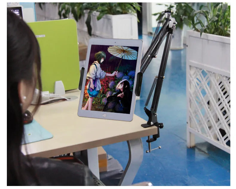 A black adjustable stand holding a mobile phone on a table.