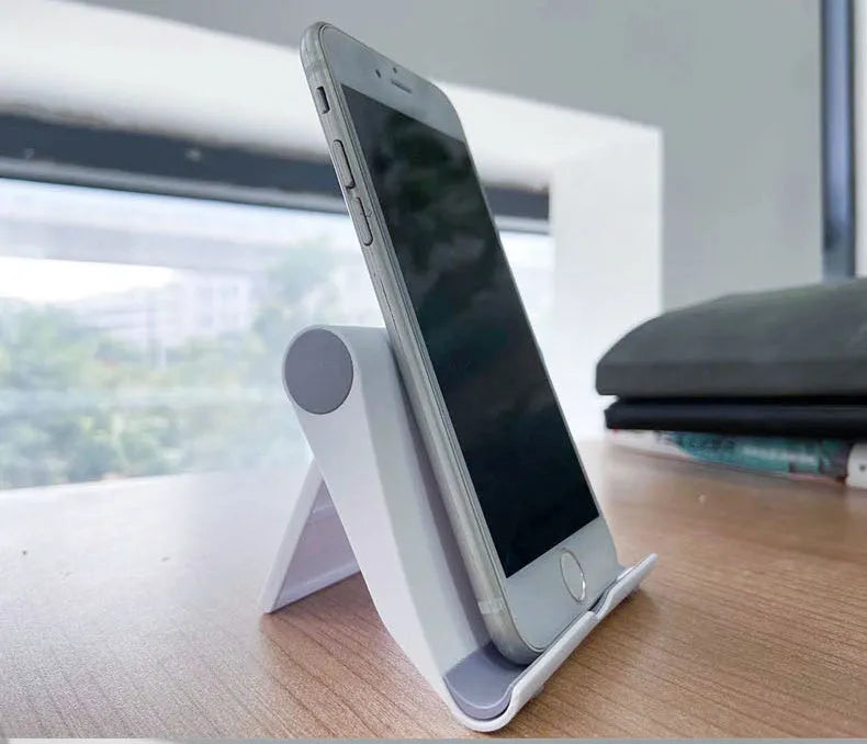 PE folding mobile phone stand in black on a wooden desktop, holding a tablet.
