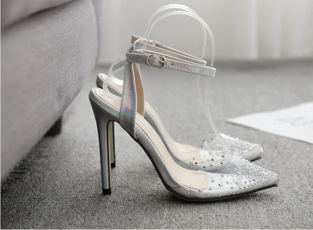 Clear PVC women's sandals with a pointed toe and a thin 10cm stiletto heel on a plain background.