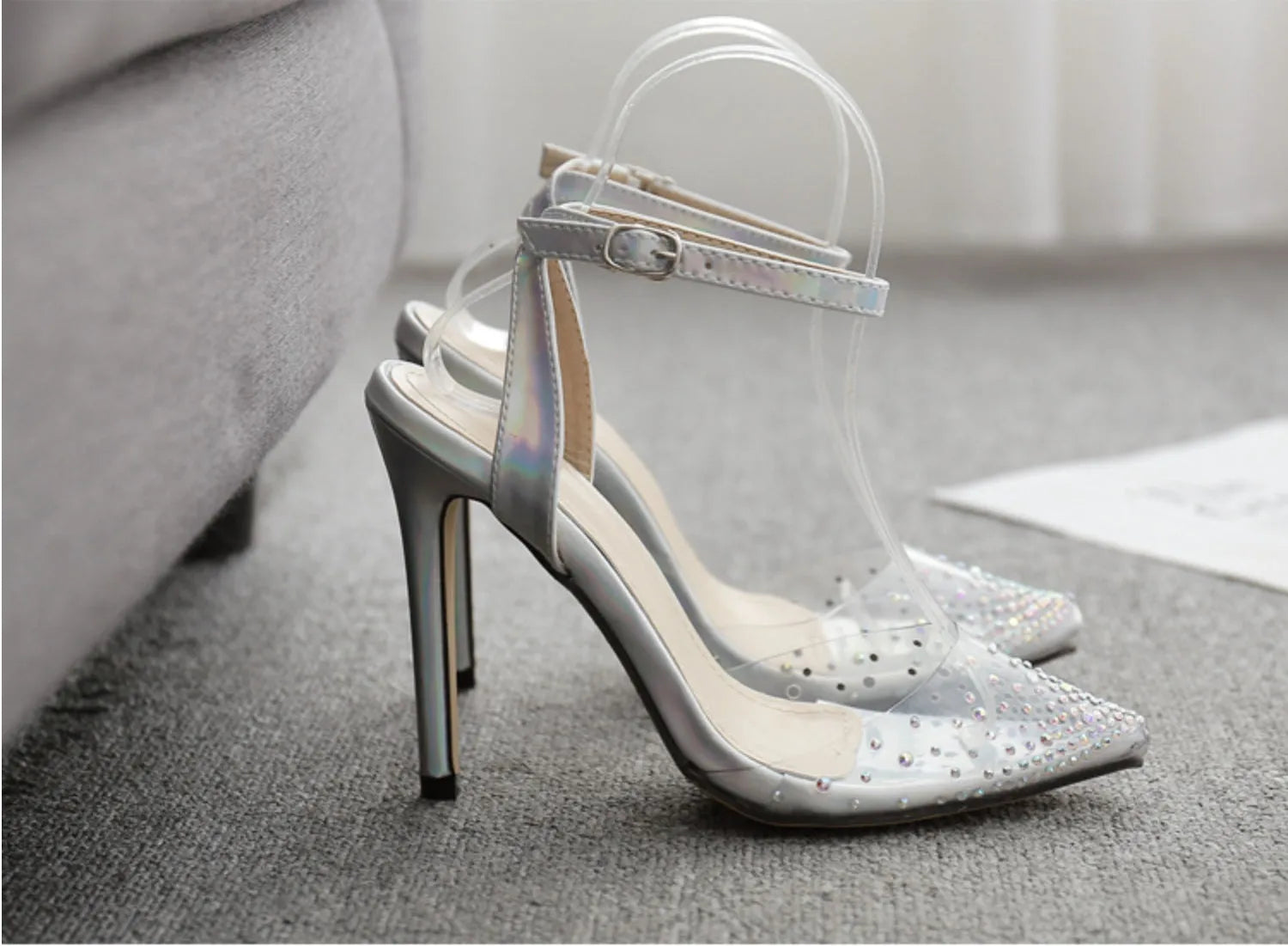Clear PVC women's sandals with a pointed toe and a thin 10cm stiletto heel on a plain background.