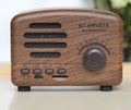 Vintage-style wood grain finish Bluetooth speaker on a table, showing compact size and USB port.